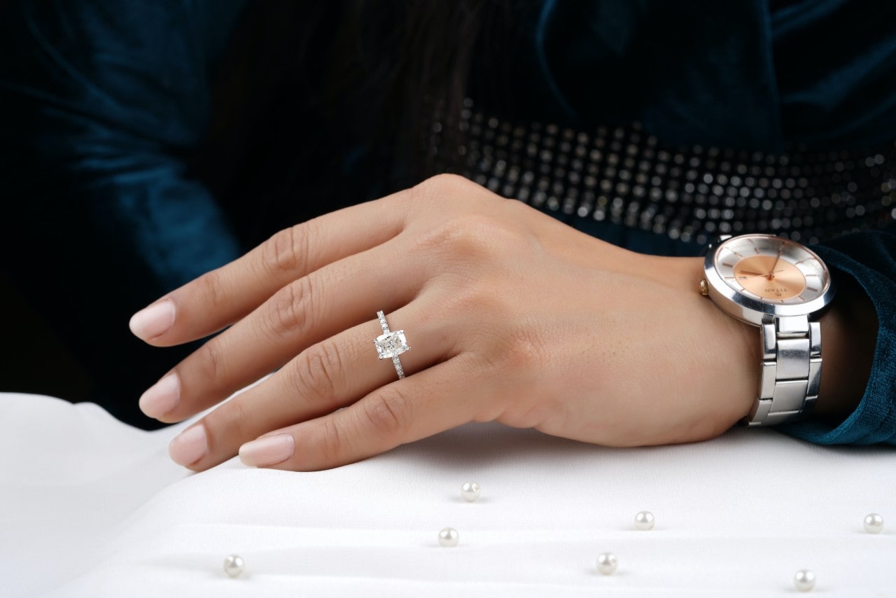 a woman wears an emerald-cut Art Deco ring and a watch.
