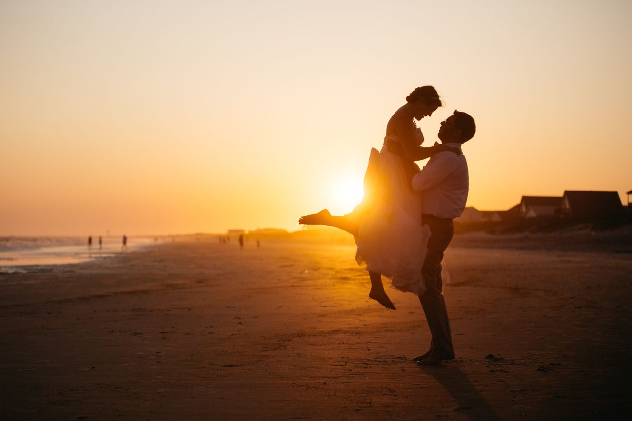 a couple embraces during sunset on a beach.