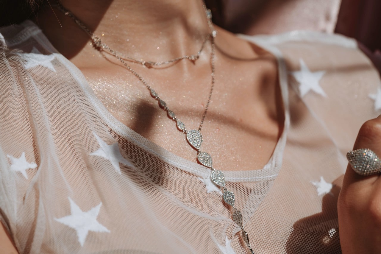 close up image of a person’s neckline adorned with two silver necklaces