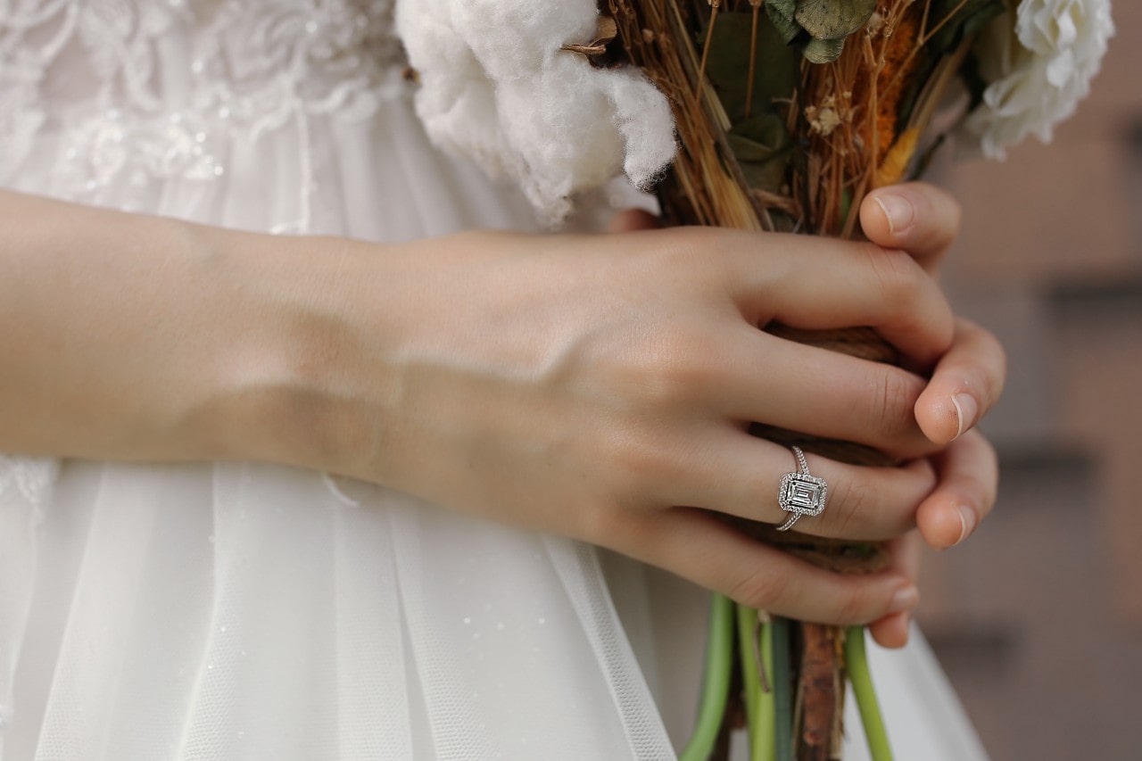 a bride holding her bouquet and wearing a silver radiant cut engagement ring