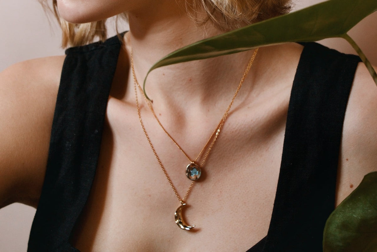 A gold crescent moon pendant and a blue topaz necklace