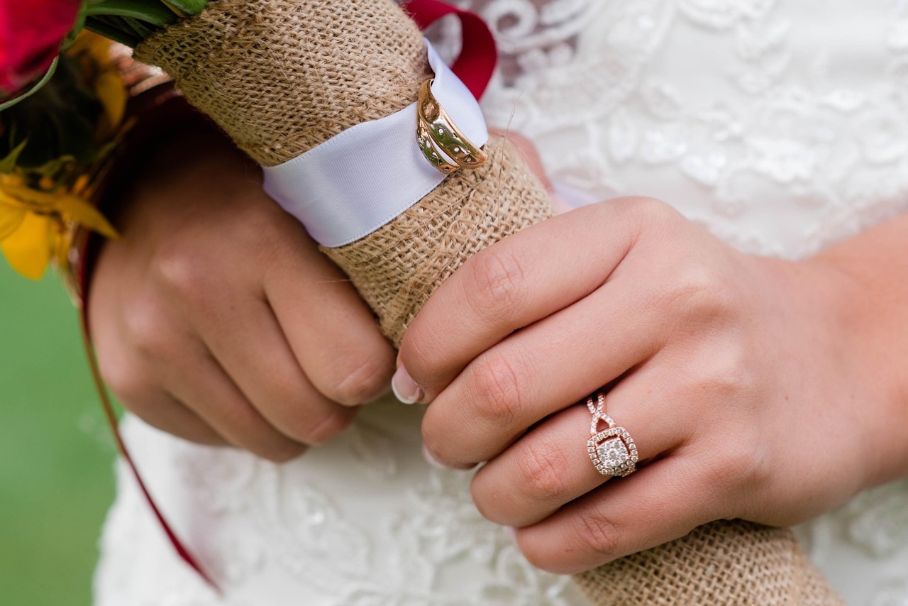 A close up of a bride holding a bouquet, showcasing a rose gold halo diamond ring.