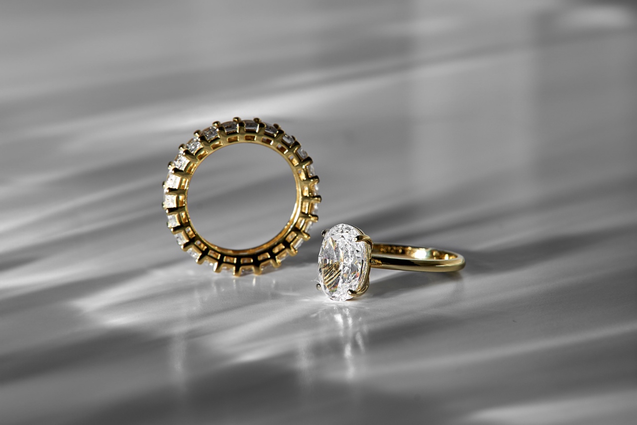 An oval cut engagement ring displayed next to a gold diamond eternity wedding band.