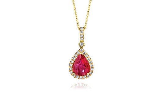 a yellow gold pendant necklace featuring a halo set ruby