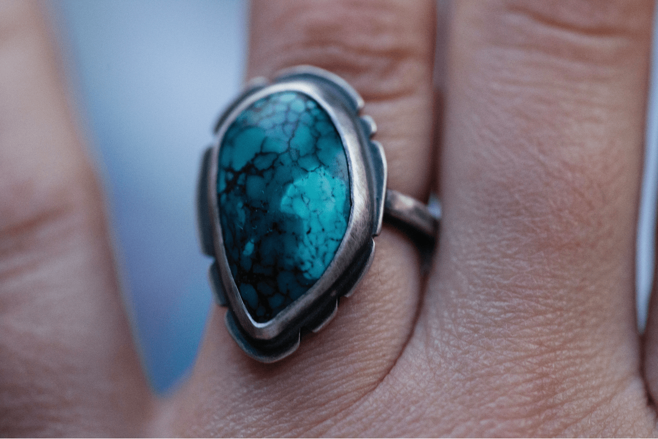 close up image of a hand wearing a white gold and turquoise ring