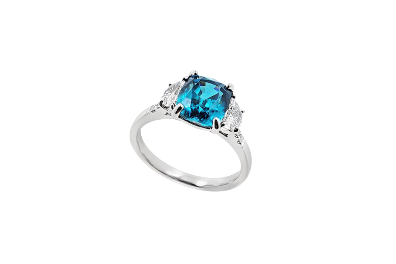 A white gold ring with a blue cambodia zircon center stone and two diamond stones accenting the sides.