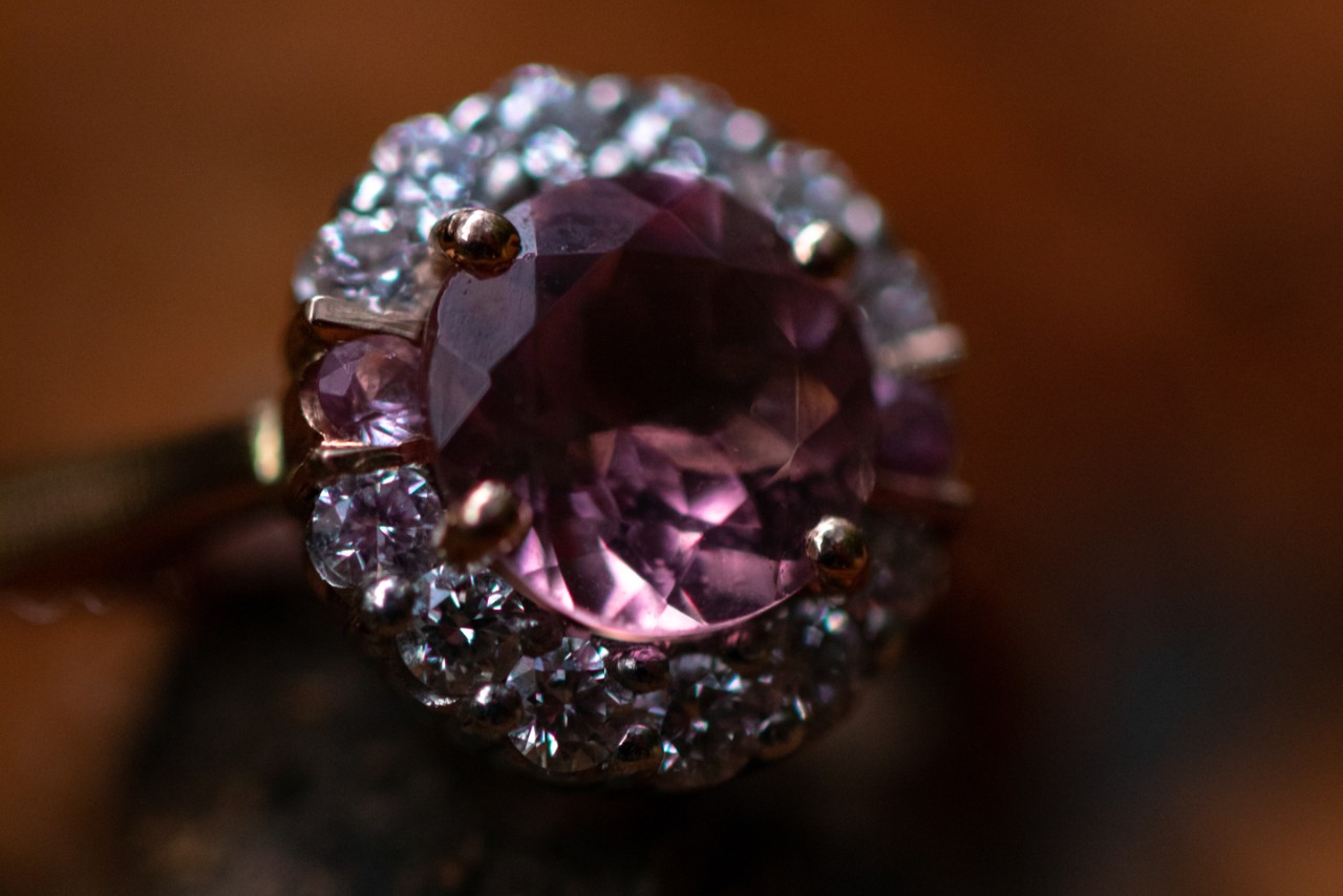 An amethyst halo fashion ring sits on the ground.