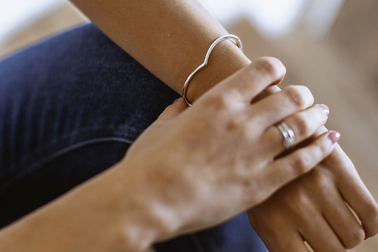 A close-up of a woman’s wrist, adorned with a sterling silver bangle and rings.