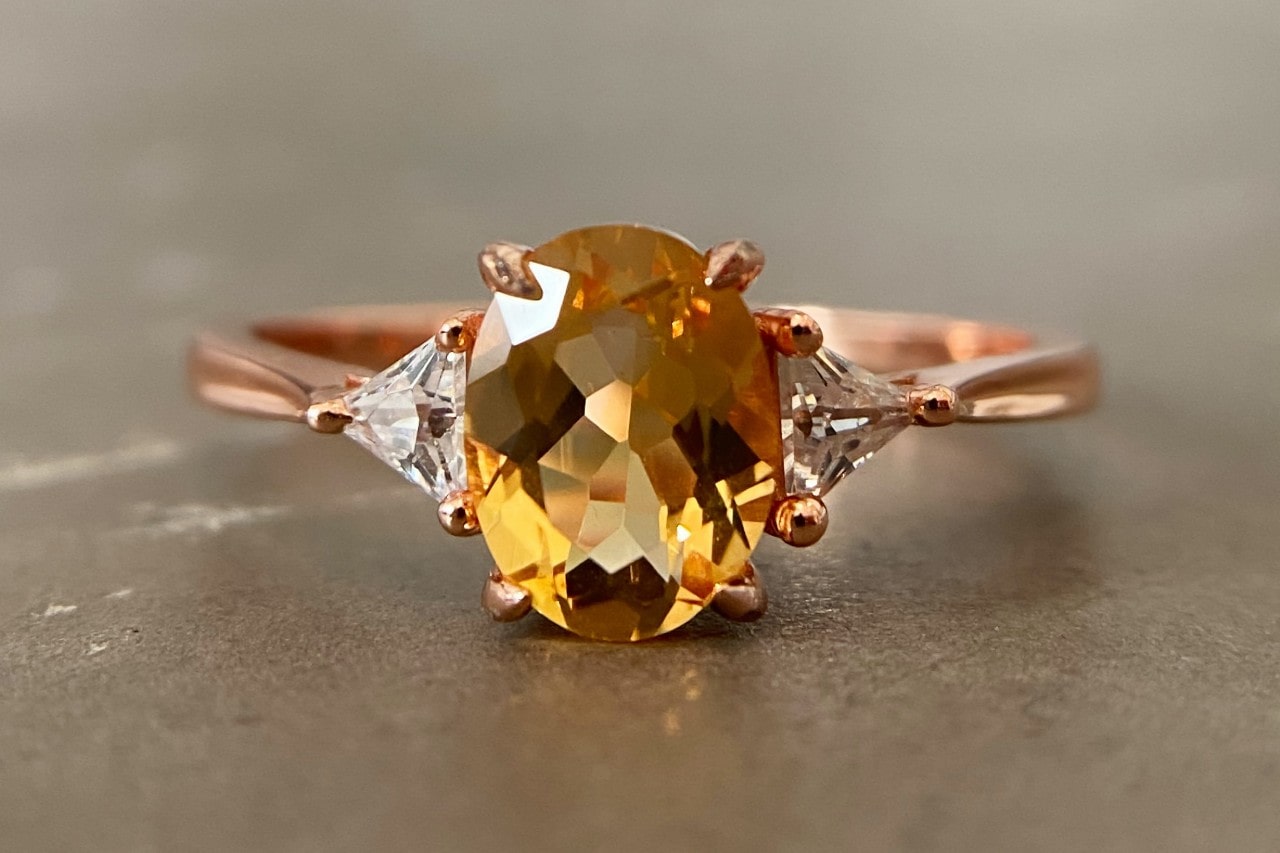 a rose gold ring featuring a citrine center stone and two diamond side stones