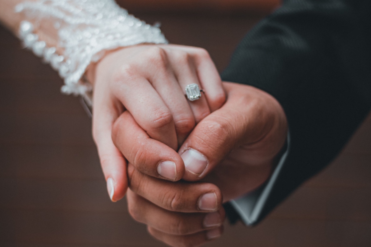 A couple holding hands, showcasing the bride’s emerald cut engagement ring.