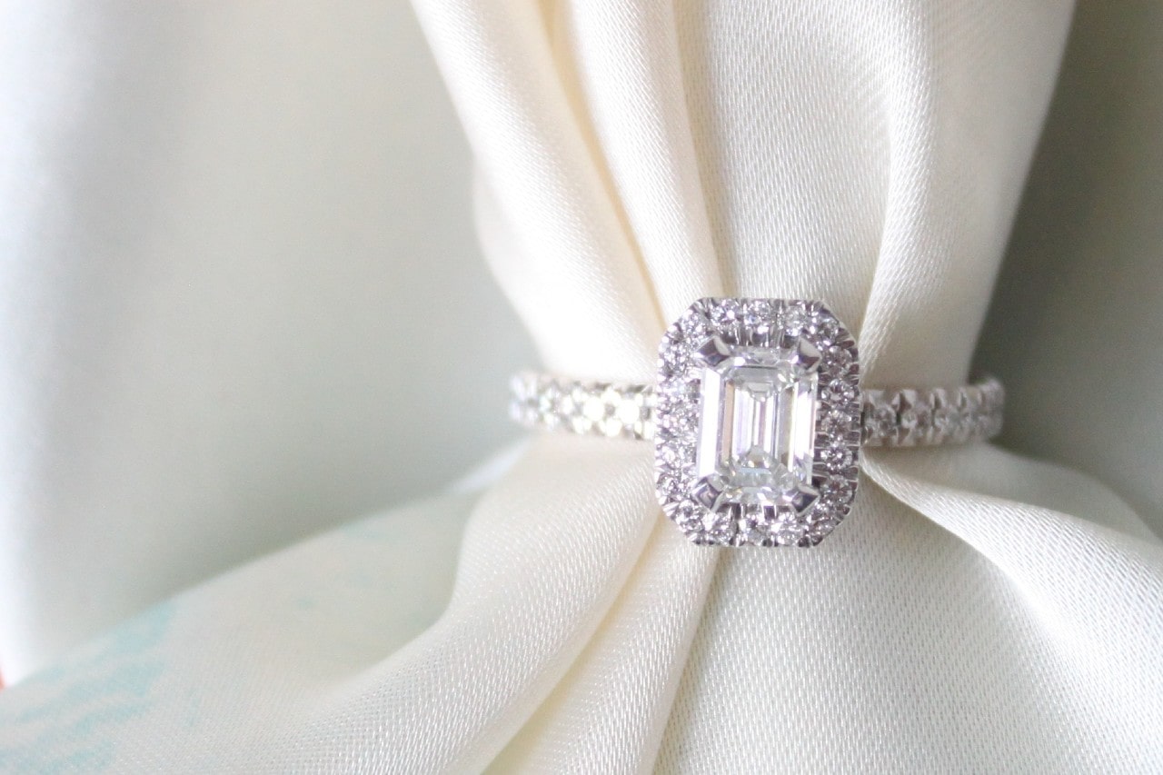 a white gold emerald cut engagement ring on a piece of white cloth