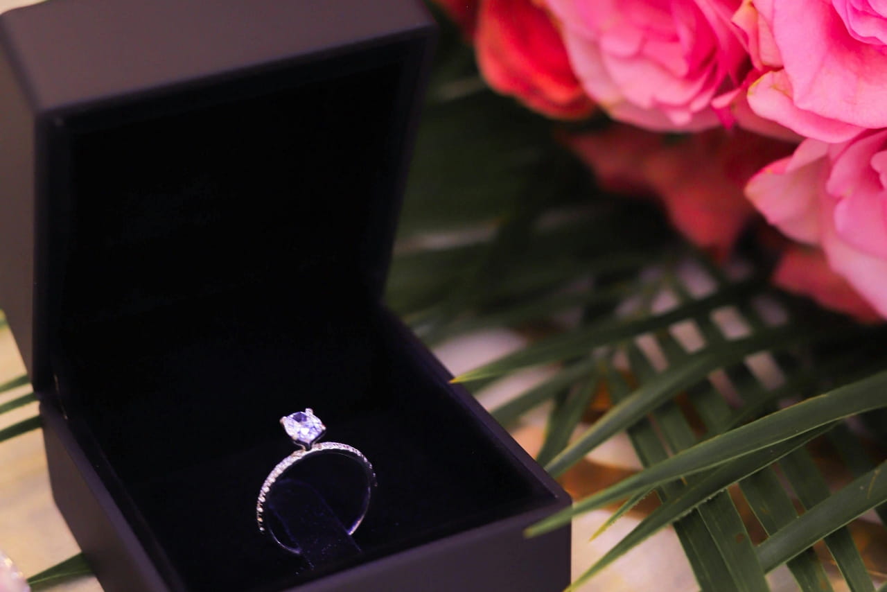 A diamond engagement ring inside a black jewelry box.
