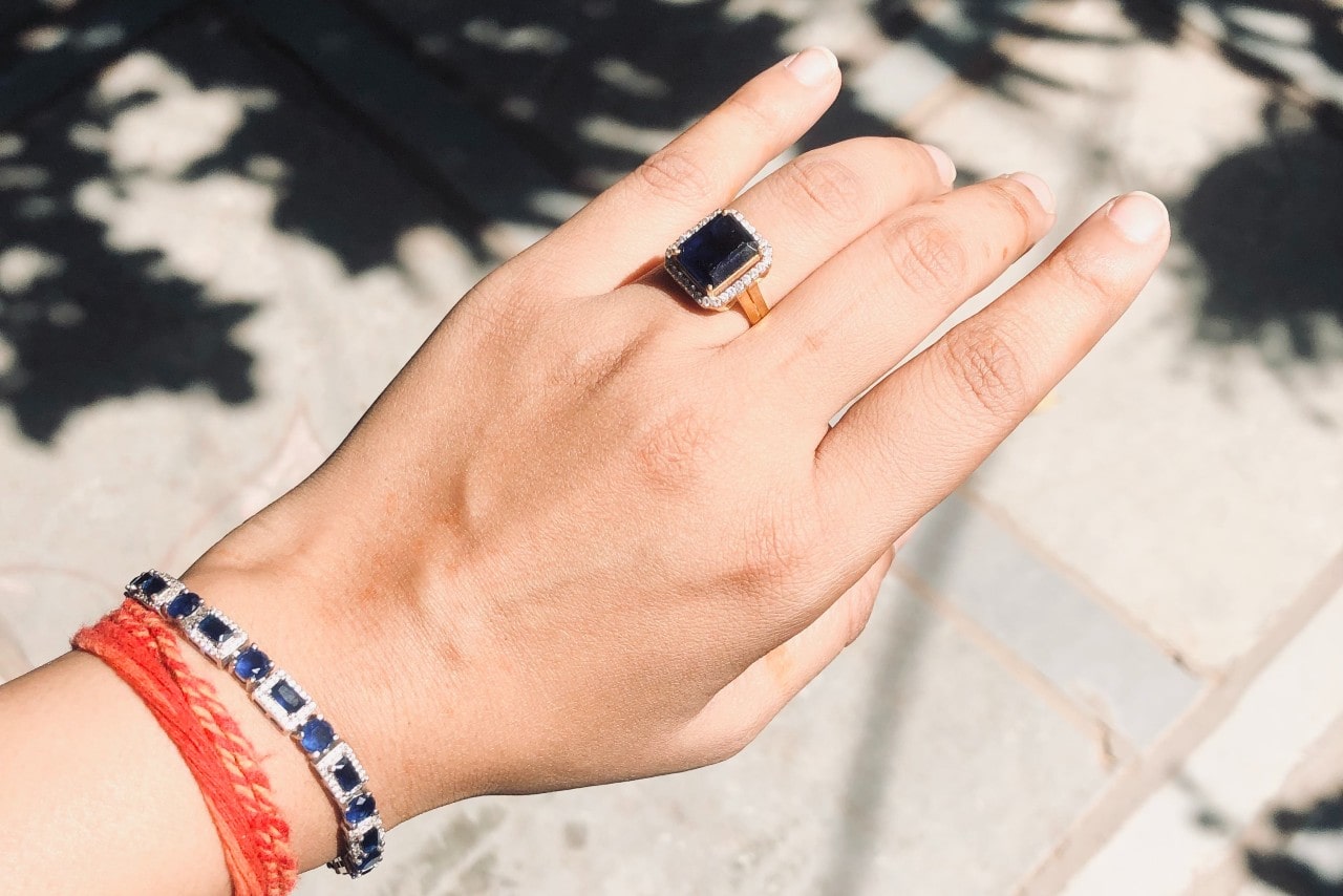 an extended hand donning a tanzanite ring and bracelet outdoors