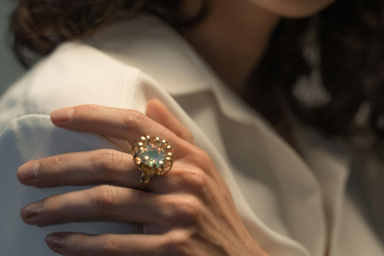 Close-up of a woman's hand resting on her shoulder, wearing a beautiful diamond ring.