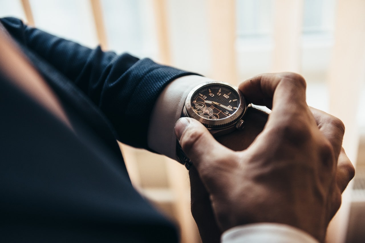 A close-up of a man in a suit adjusting his elegant luxury watch.