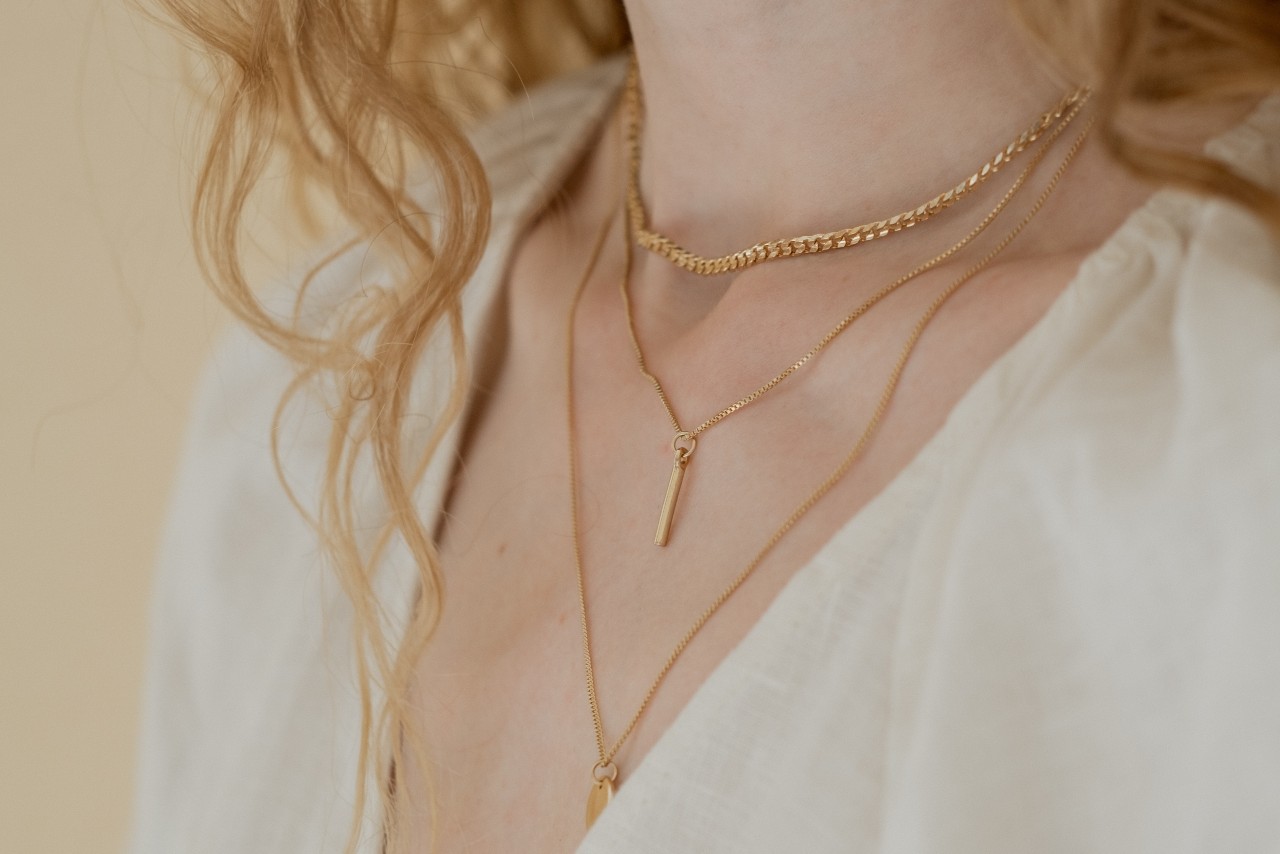 close up image of a woman’s neck adorned with three gold necklaces of varying lengths