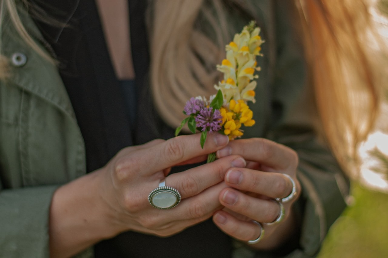 lady’s hands wearing fashion rings and holding flowers