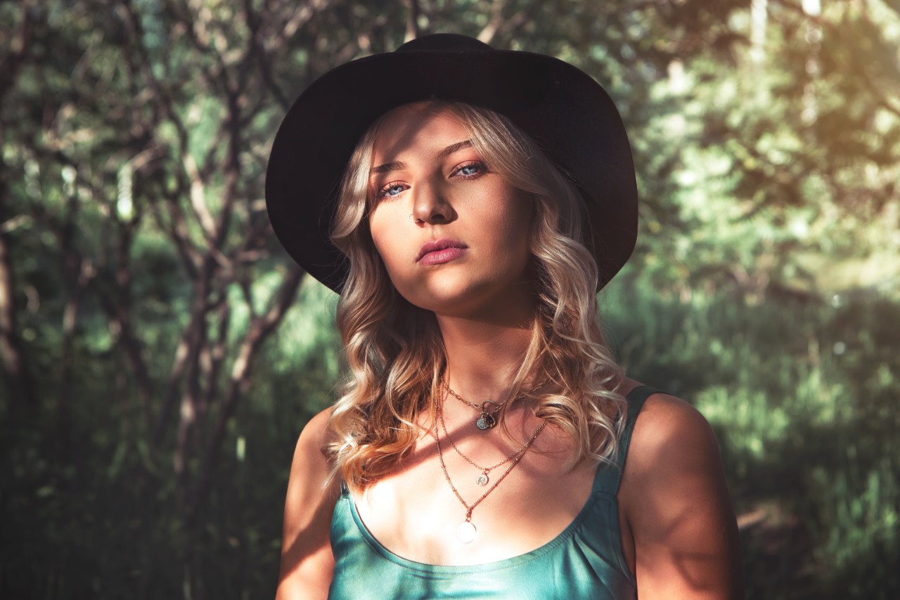 lady wearing a hat and fashion jewelry with a nature background