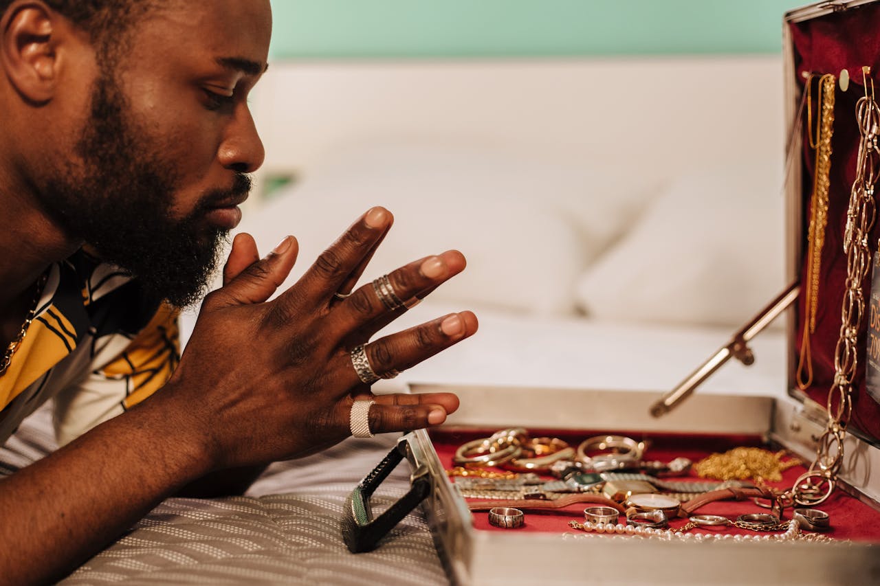 A man sits in front of an open case full of gold jewelry and timepieces.