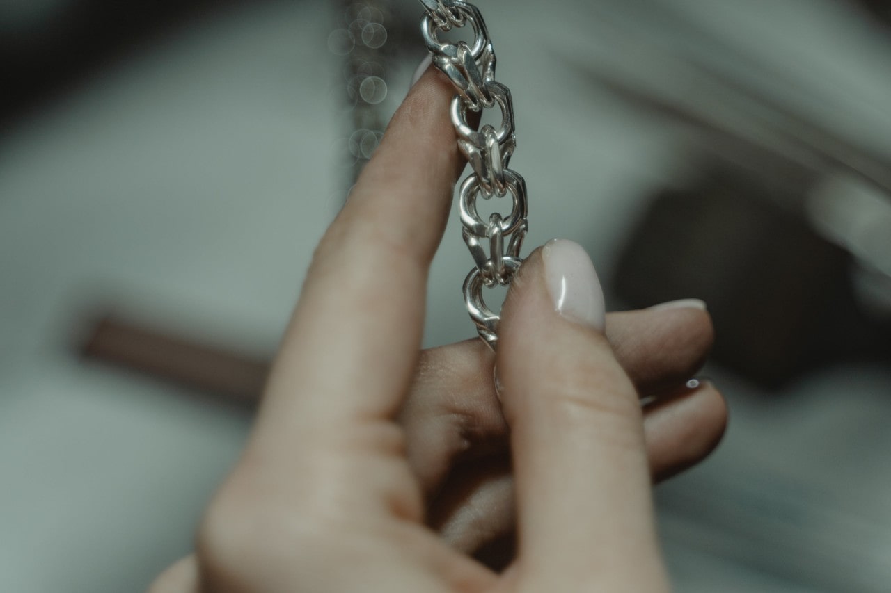 A woman inspects a chain necklace.