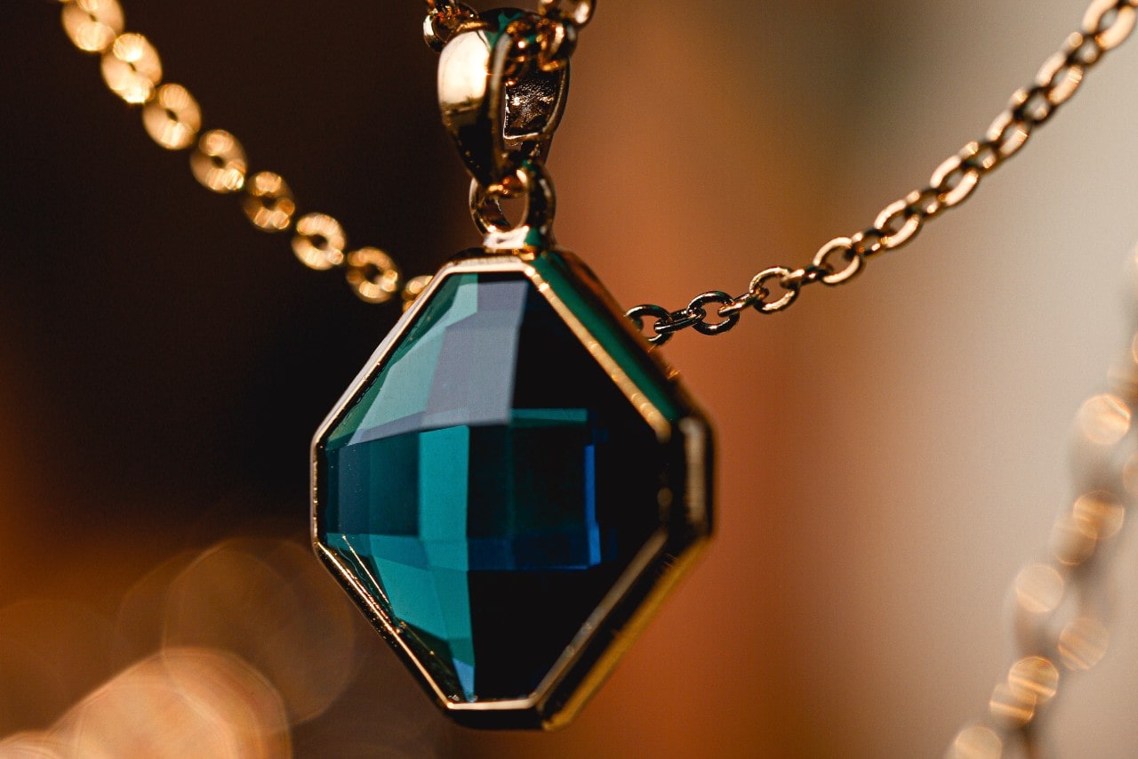 A closeup view of a dark blue gemstone set in a yellow gold pendant.