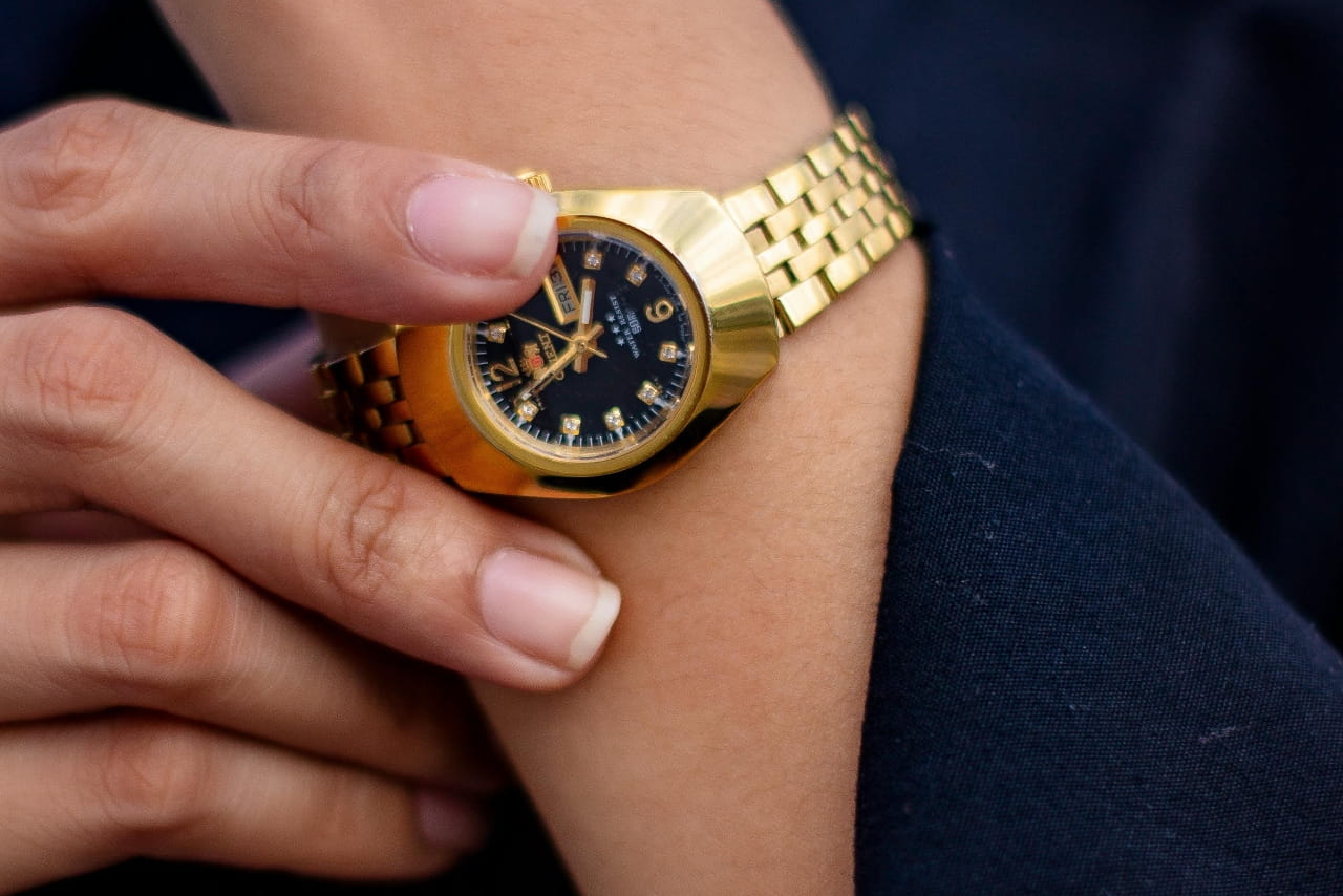 Close-up of a person's wrist wearing a gold watch with a black face.