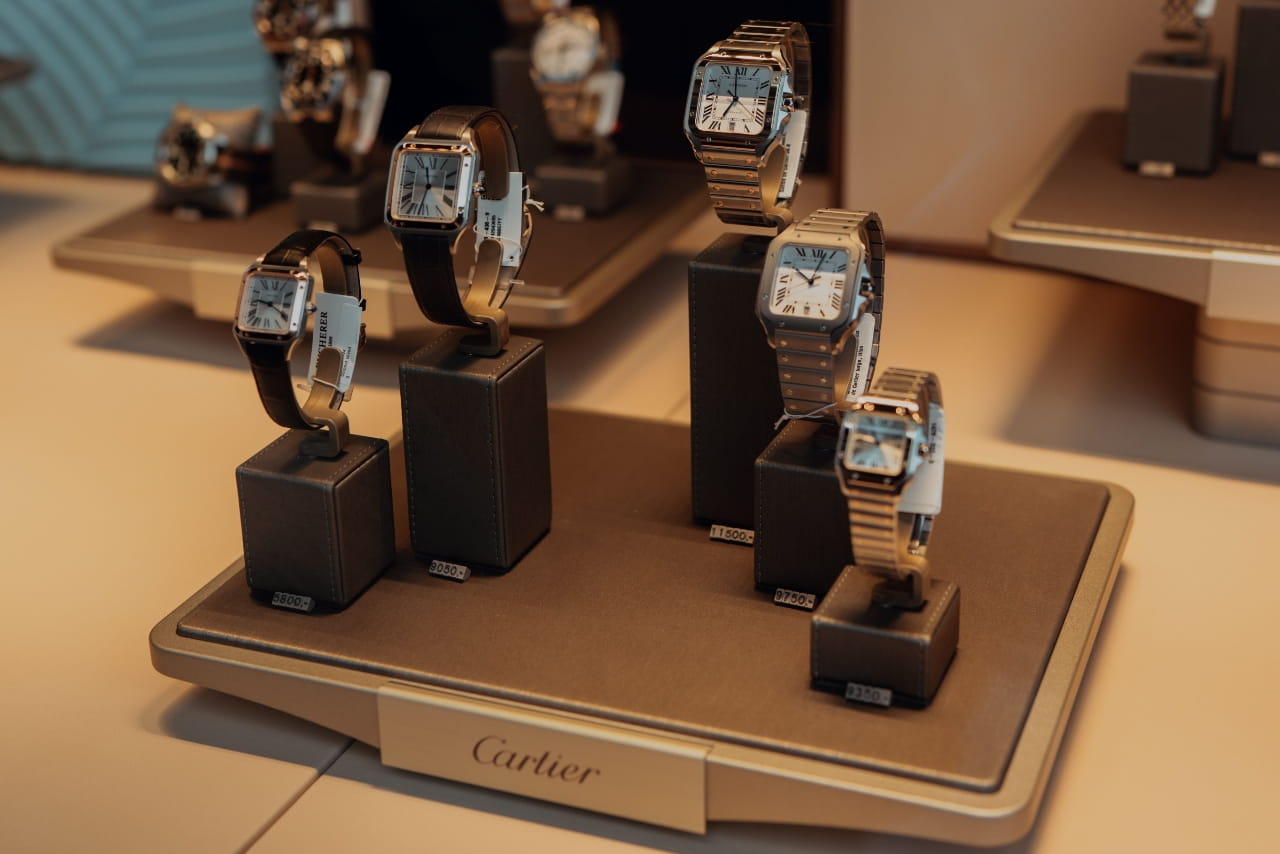 Display of Cartier watches on stands with leather and metal bands, in a luxurious boutique.
