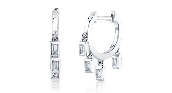 a pair of white gold huggie earrings featuring bezel set, baguette cut diamonds