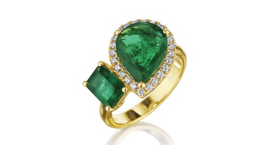 a yellow gold toi et moi ring featuring two emeralds and a diamond halo