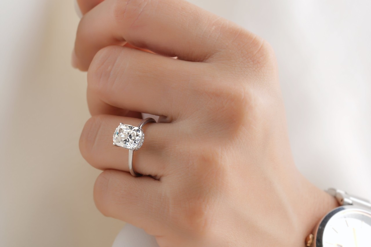 A closeup of a woman’s hand wearing a platinum oval-cut diamond ring.
