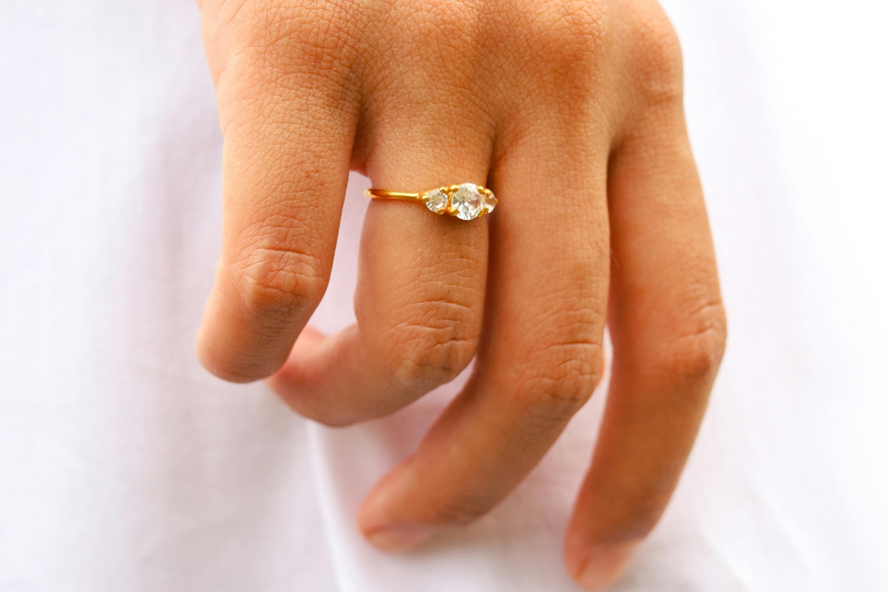 A yellow gold three stone engagement ring on a woman’s hand.