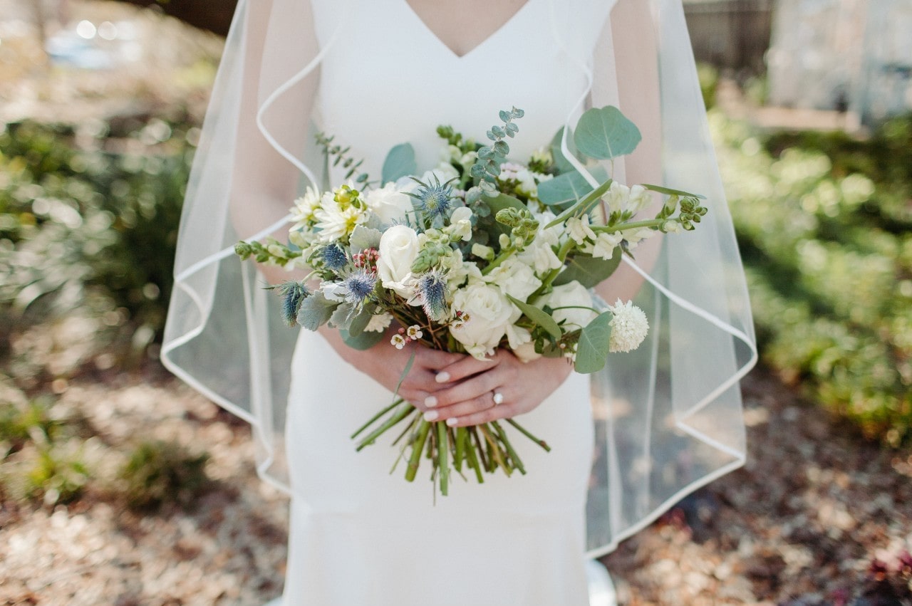 a bride holding her bouquet outdoors and wearing an engagement ring