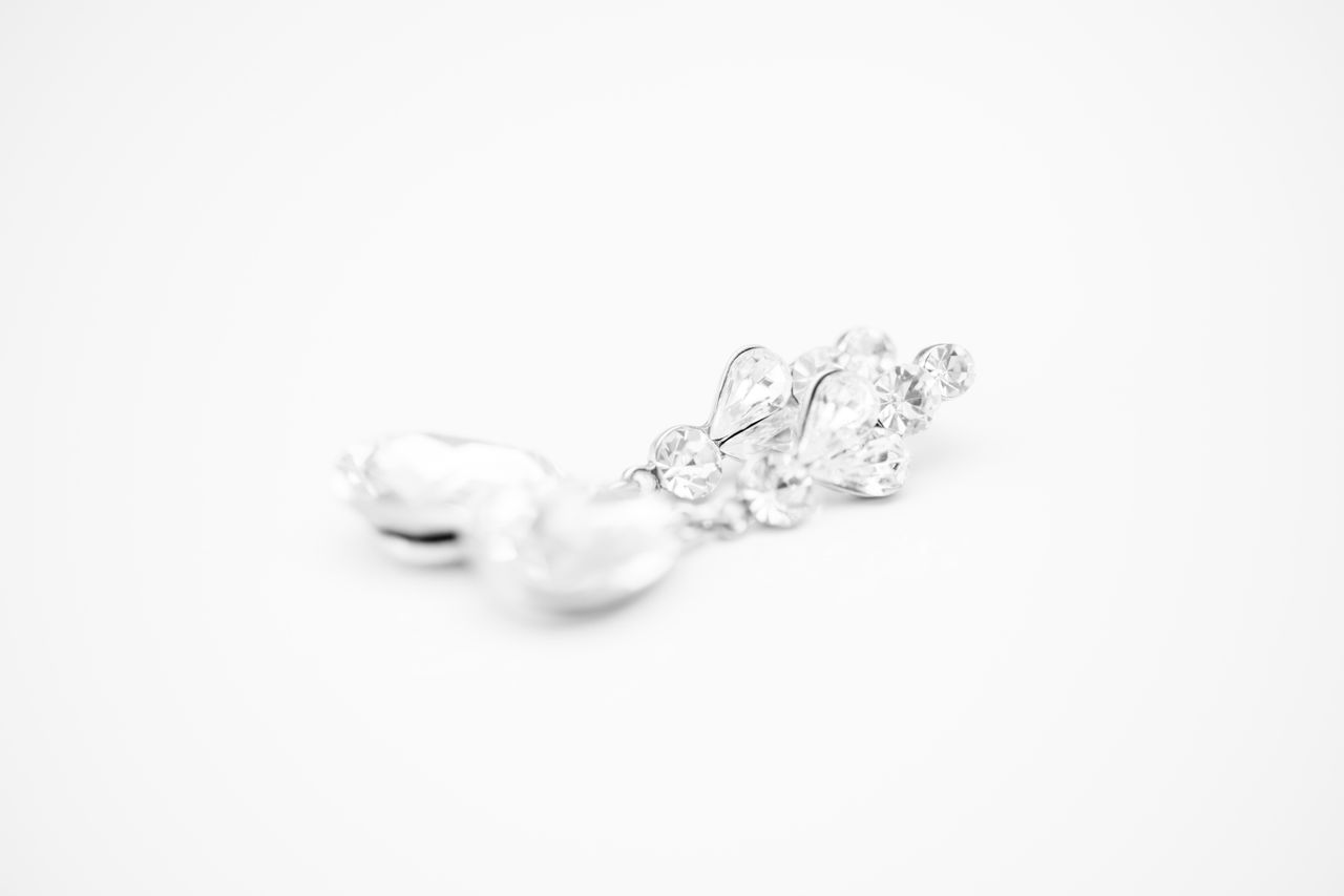 A white gold drop pearl earrings on a white surface