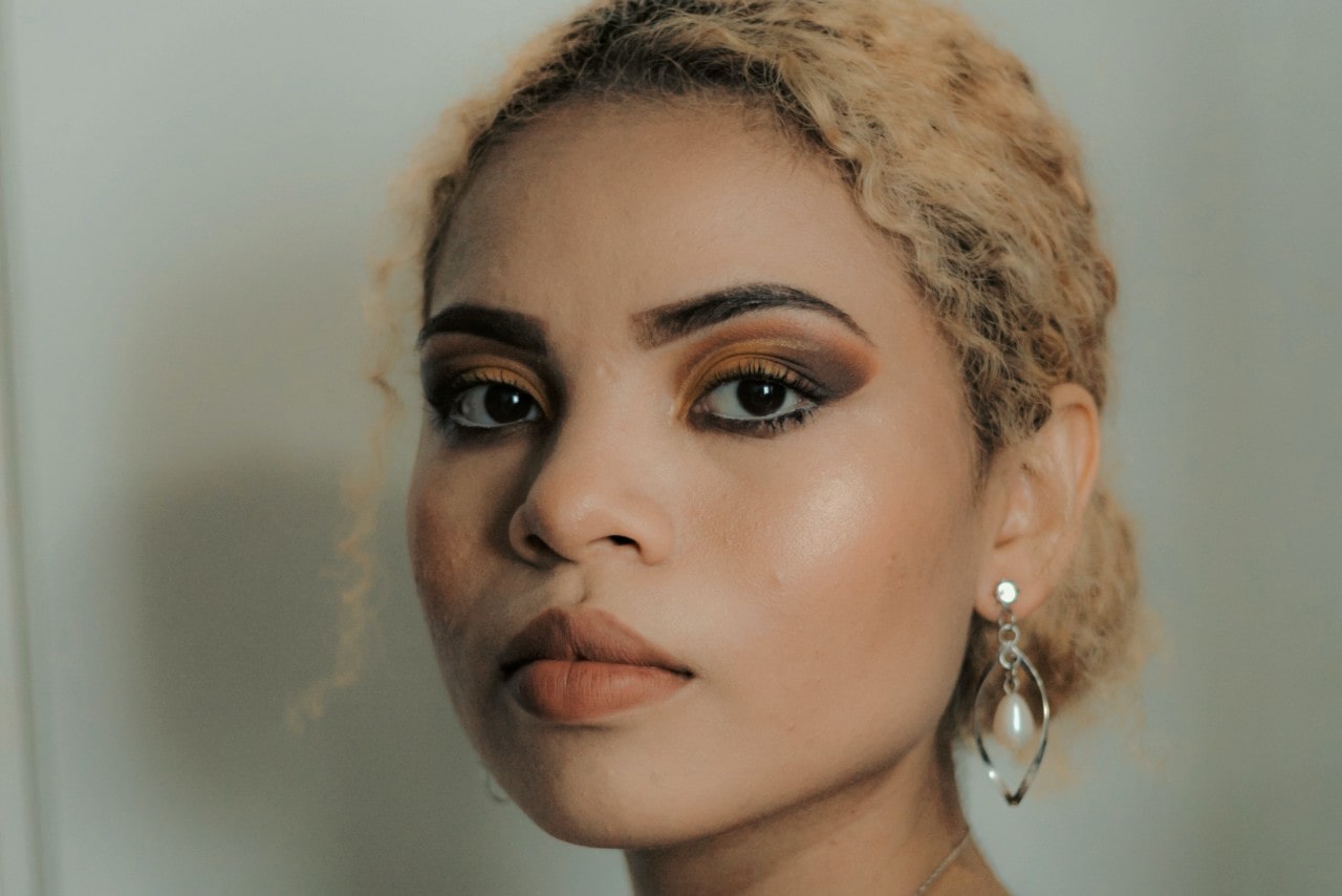 A close up of a woman with blond curly hair, wearing drop pear sterling earrings.