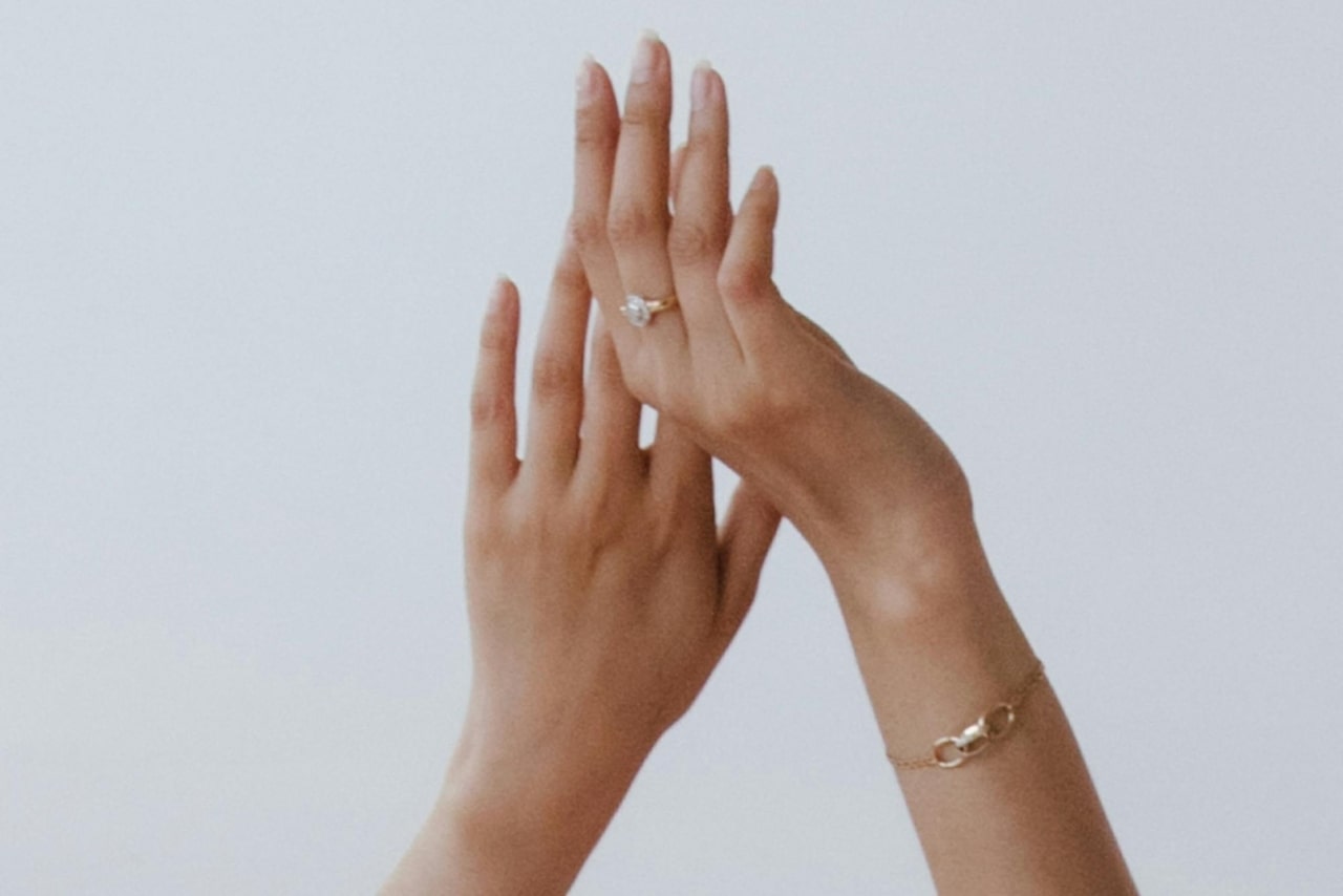 A close-up of two hands reaching toward the sky, one hand adorned with a beautiful gold ring.