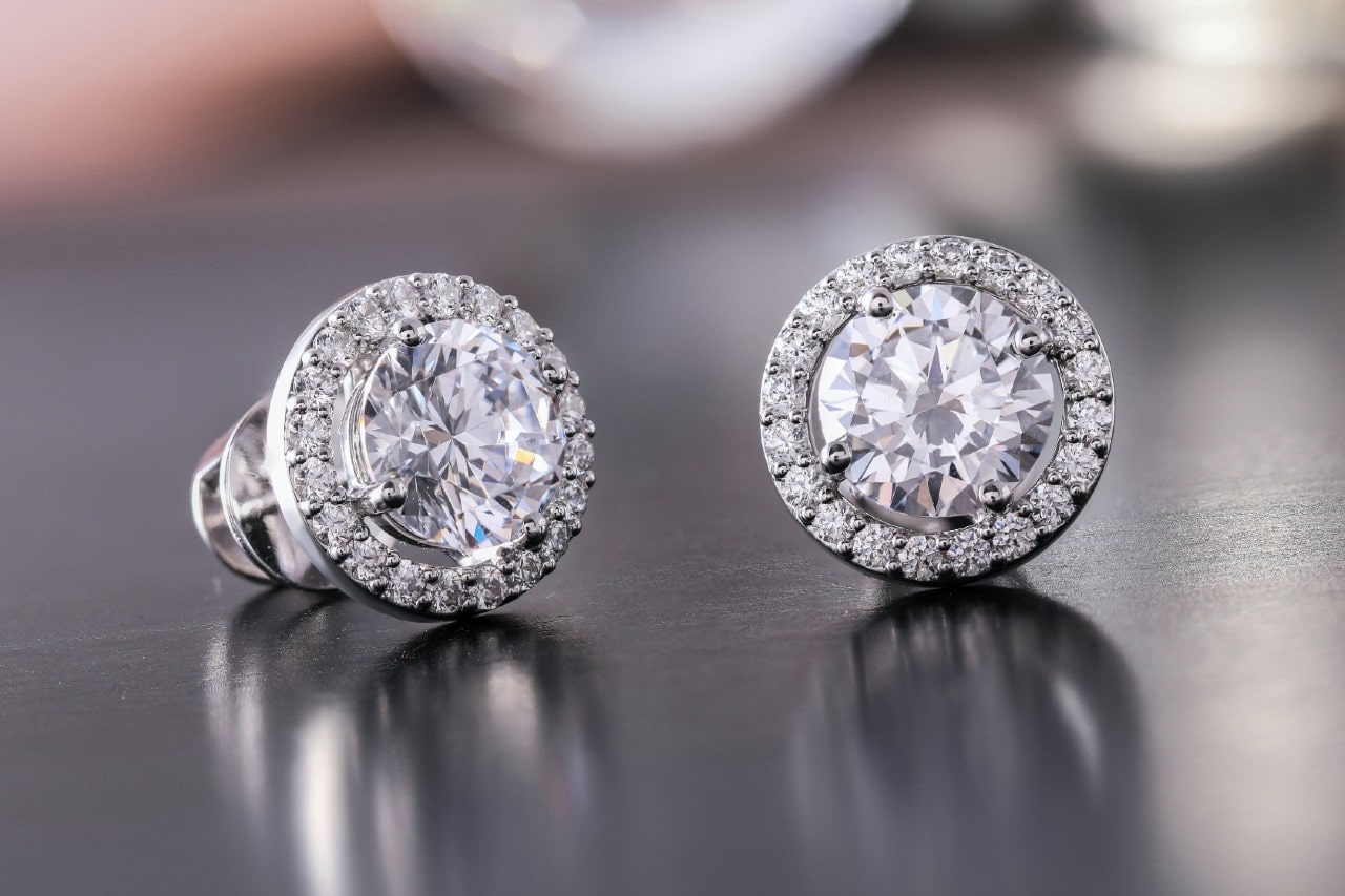 a pair of white gold diamond stud earrings on a shiny metal surface