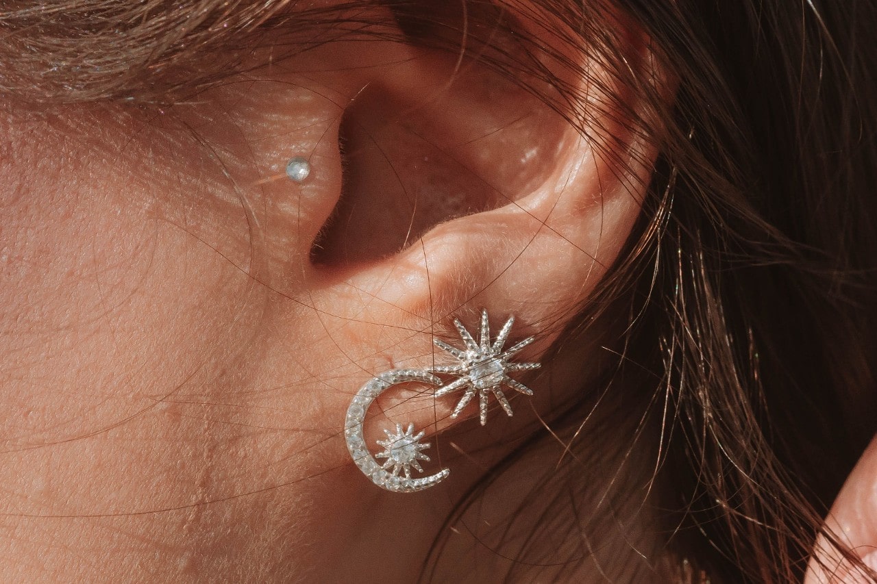 close up image of a woman’s ear donning sun and moon diamond stud earrings