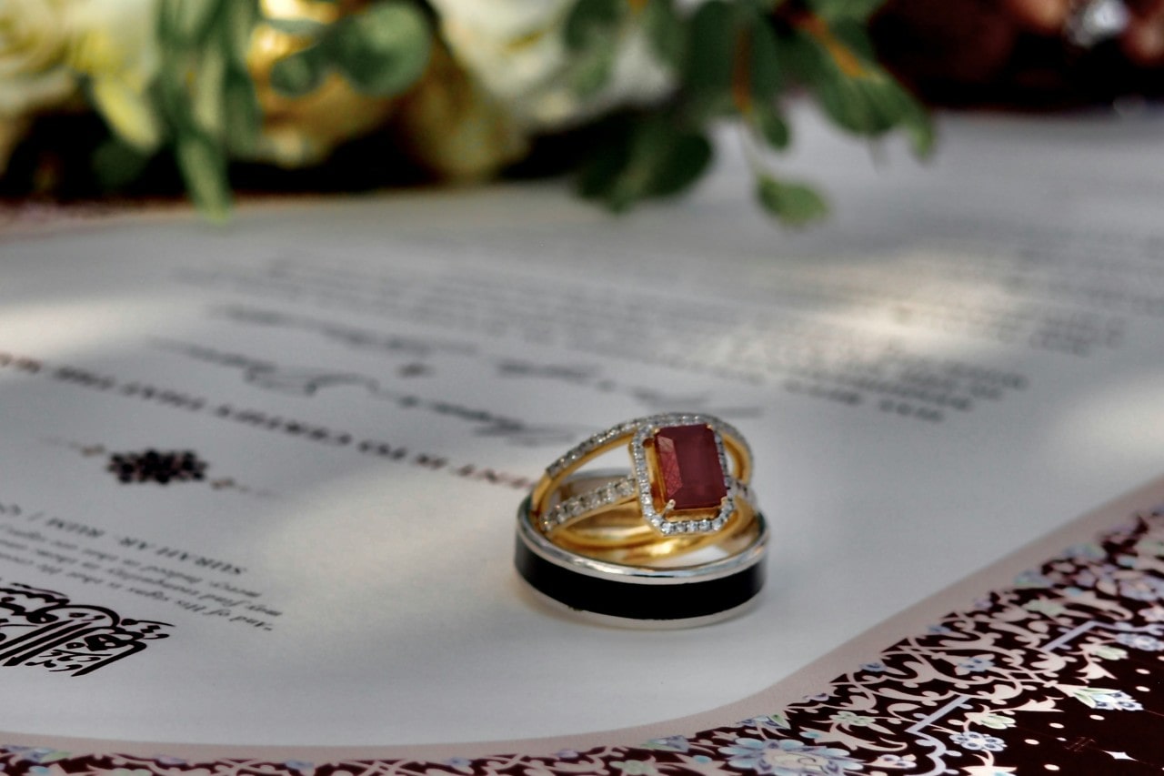 a pair of wedding bands and engagement ring featuring a red center stone stacked